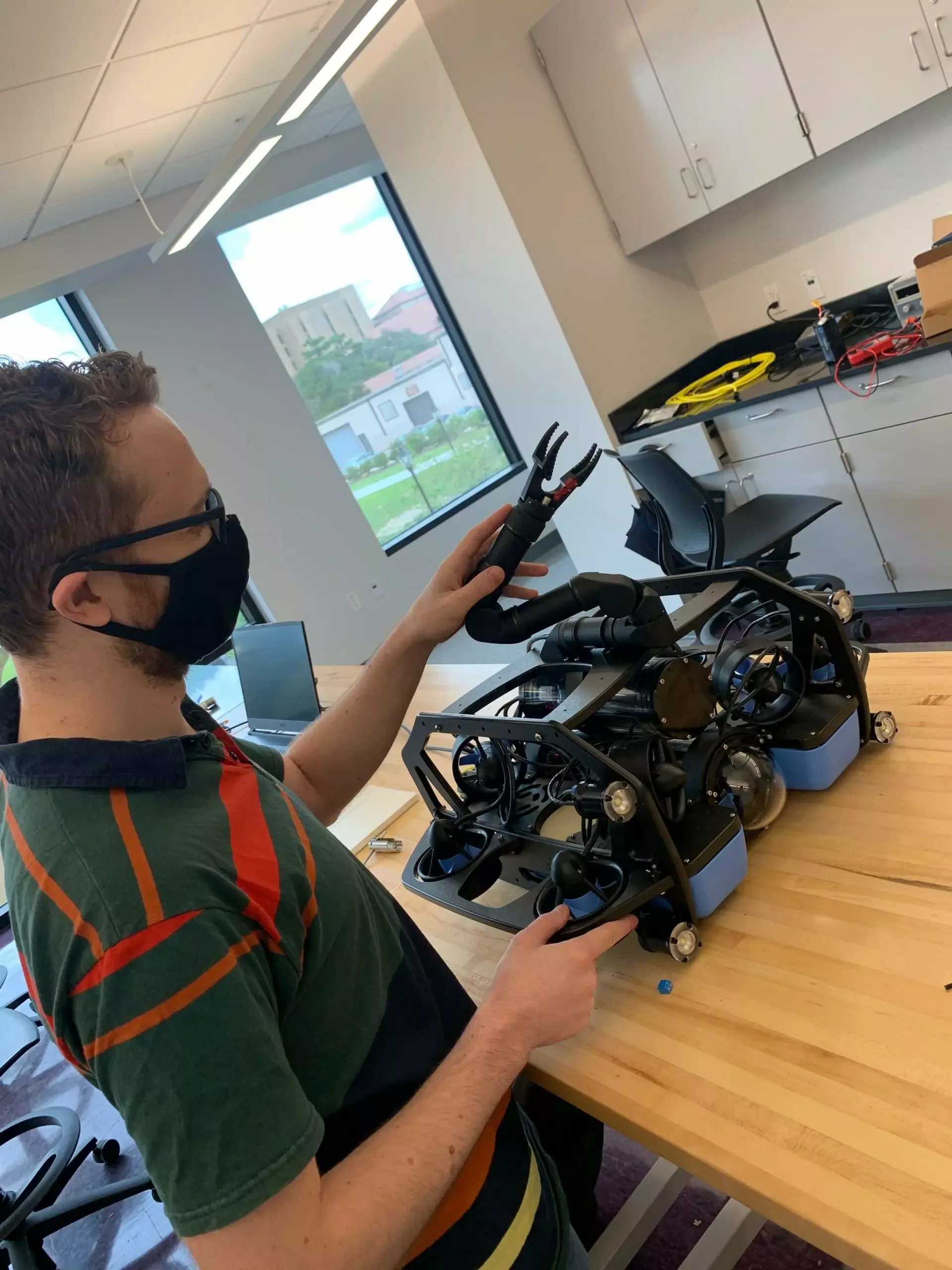 A RkinD member adjusting a Reach Robotics manipulator