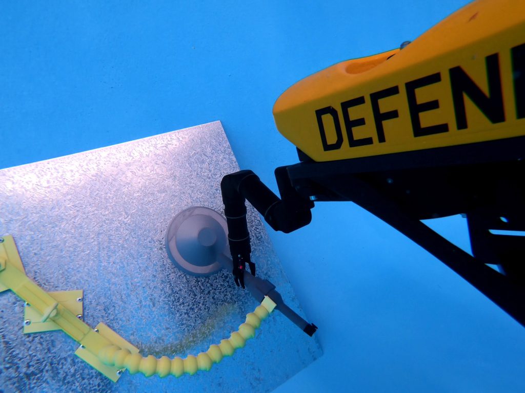 A VideoRay MSS Defender equipped with Reach Robotics Reach 5 Mini underwater robotic arm carries out intervention trials